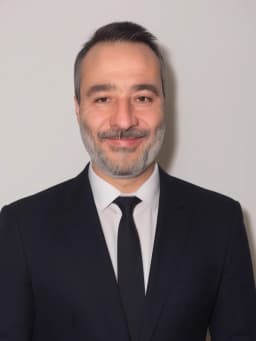 Portrait IA par PhotoMaintenant d'un homme en costume noir devant un arriere plan blanc